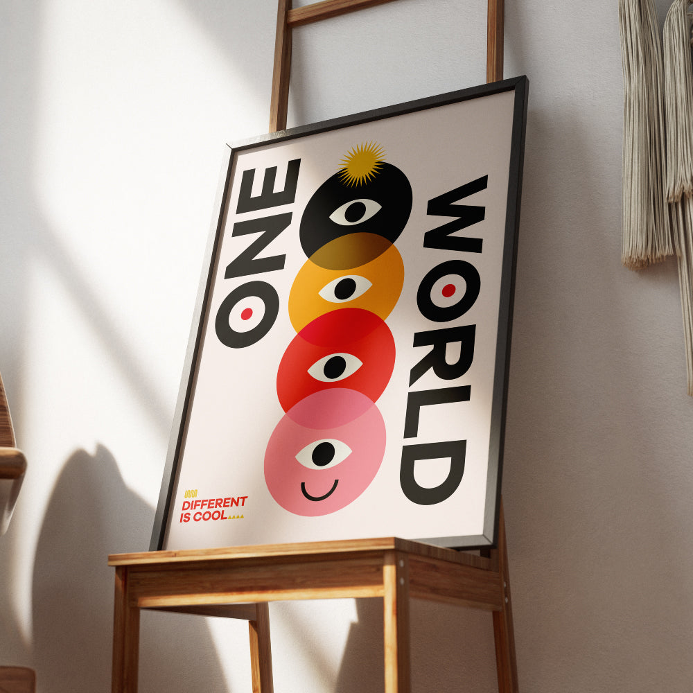 Poster con il testo 'One World' accompagnato da un design geometrico colorato con cerchi sovrapposti in nero, giallo, rosso e rosa, ciascuno contenente un occhio stilizzato e un volto sorridente nell'ultimo cerchio. In basso a sinistra la scritta 'Different is Cool'. Design moderno e simbolico su sfondo chiaro.